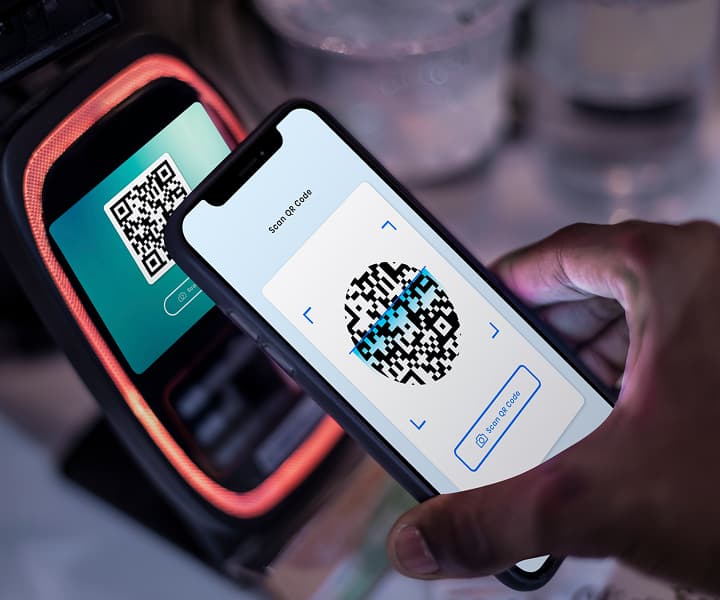 Smartphone scanning a QR code for cashless payment near a terminal