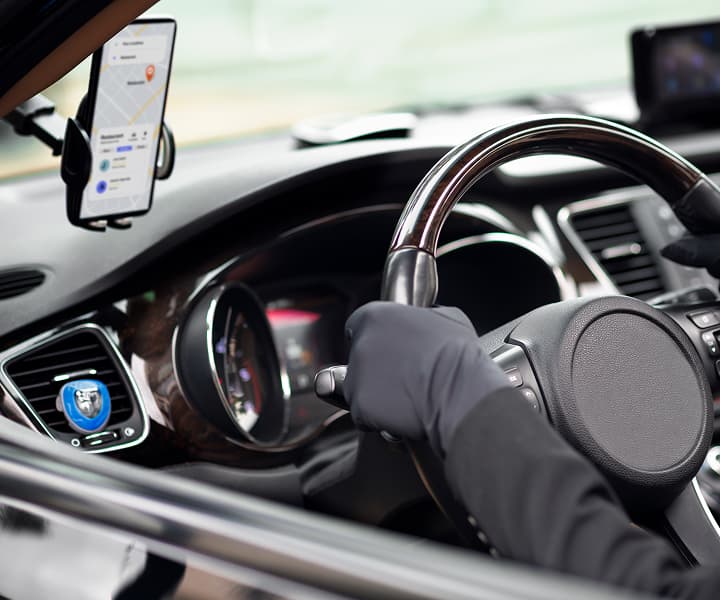 Hand on a car steering wheel with a phone mounted for taxi service use